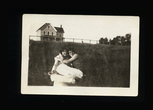 vintage snapshot photo affectionate hugging girlfriends - house on hill in background