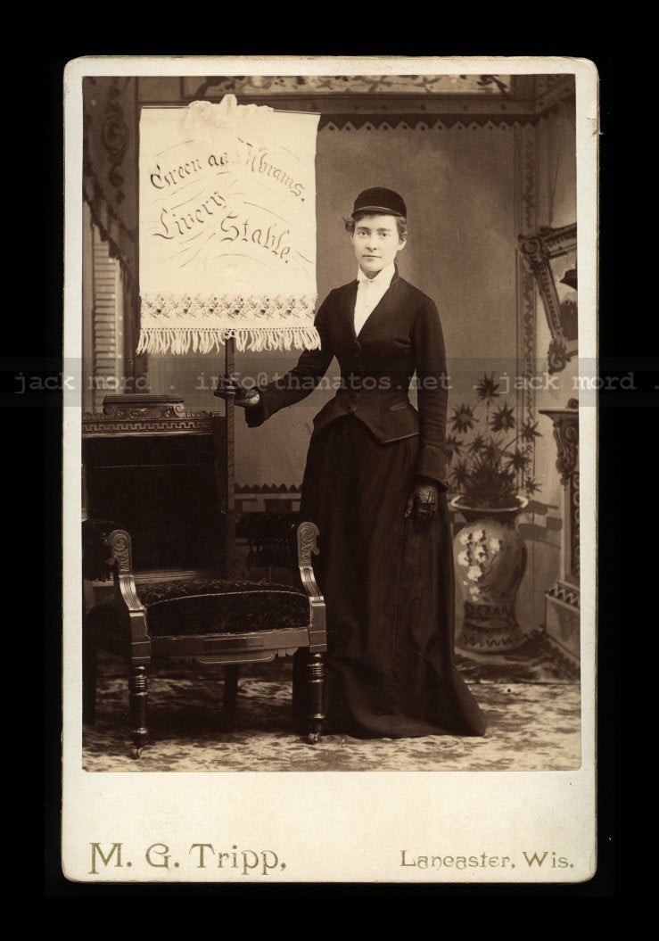 Lady Holding Advertising Banner For Green & Abrams Livery Stable / Wisconsin